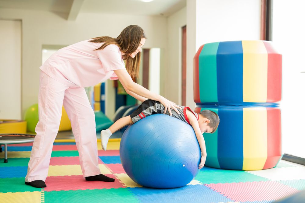 Therapist helping child on a large therapy ball