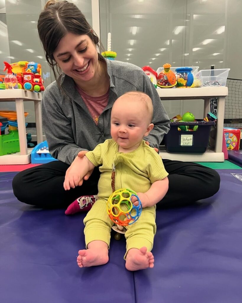 Therapist playing with smiling baby on a mat