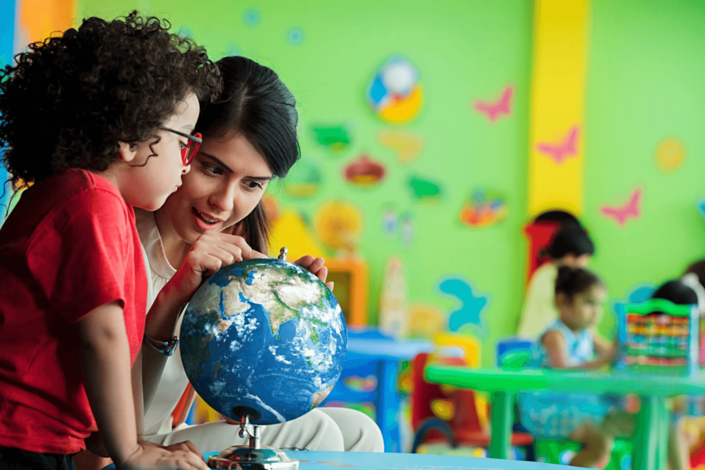 Teacher showing globe to preschool child