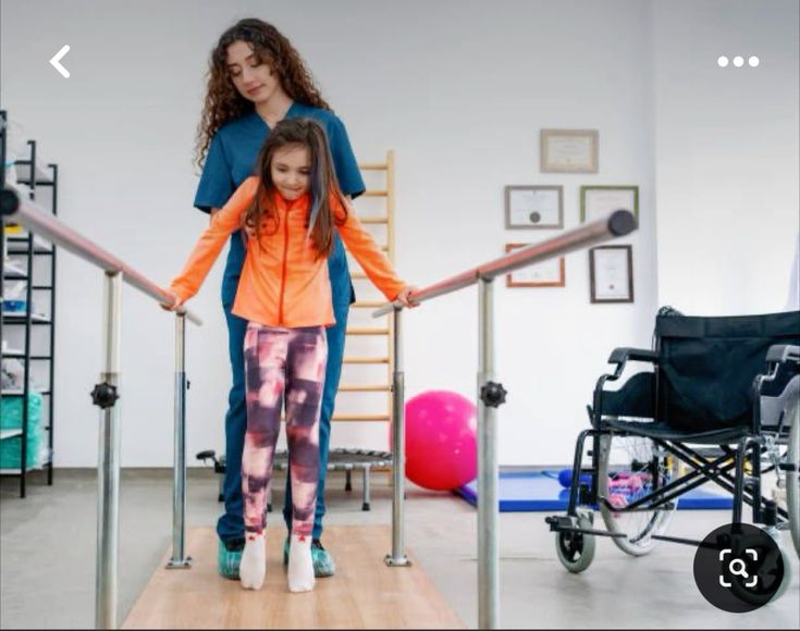 Therapist assisting child with parallel bar walking exercise