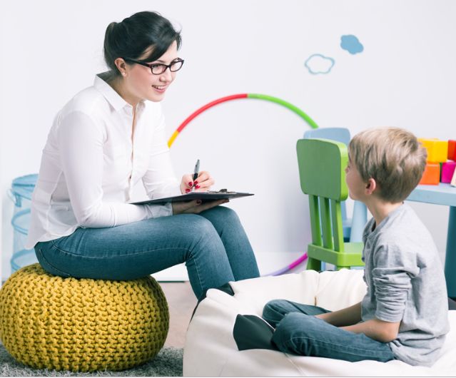 Teacher talking to a young boy during a learning session