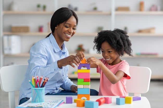 Teacher and child playing with colourful building blocks together