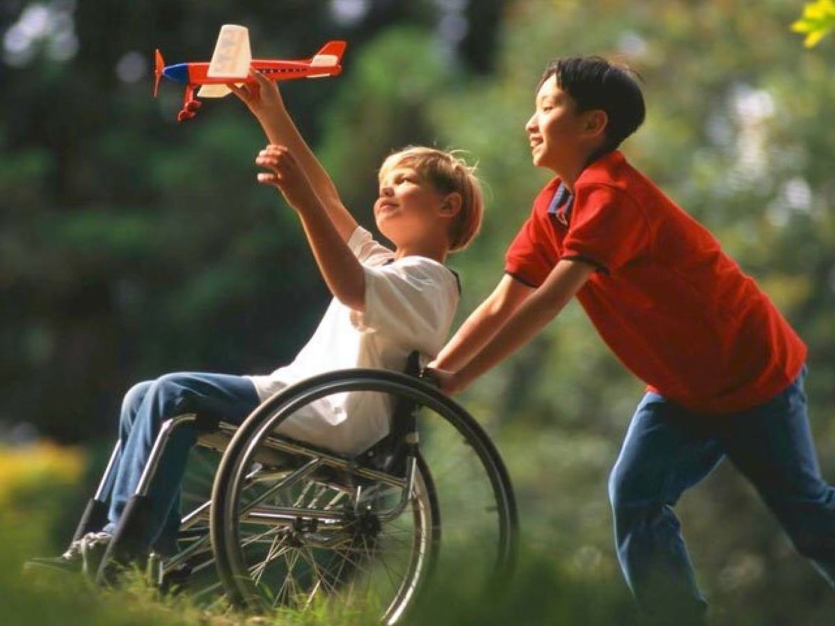Boy in wheelchair playing outdoors with friends